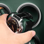 Hand placing a luxury watch into a black and green leather Aevitas watch winder with silver accents.