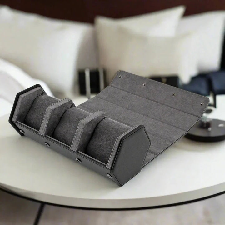 Aevitas Watch Winders’ 3 Watch Travel Case in black leather with grey lining, Hexagon Style, rests on a round white table in front of a sofa with white and beige pillows.