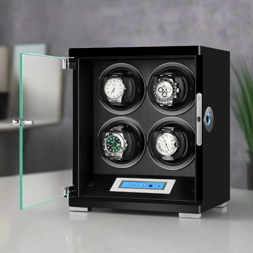 The Aevitas 4 Watch Winder from the Tower Series features a piano black wood finish, glass door, and digital control panel, beautifully displaying four automatic watches. It sits on a light surface with a blurred background.