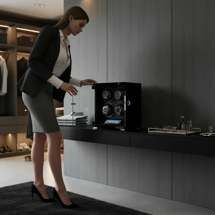 A businesswoman opens the Aevitas 4 Watch Winder Piano Black Wood Finish, The Tower Series, on a modern wall cabinet; organized automatic watches and a tidy closet appear in the background.