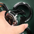 Hand placing a luxury watch into a black and green leather Aevitas watch winder with silver accents.
