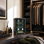 Scene of a black leather watch winder on a dressing room vanity with luxury accessories and natural daylight.