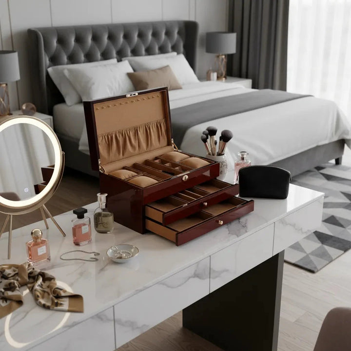 A modern bedroom features a grey upholstered bed, a marble vanity with the Aevitas Premium Jewellery Box Extra Large Size Camphor Finish, makeup brushes, perfume bottles, jewelry, scarf, round mirror, window and curtains in the background.