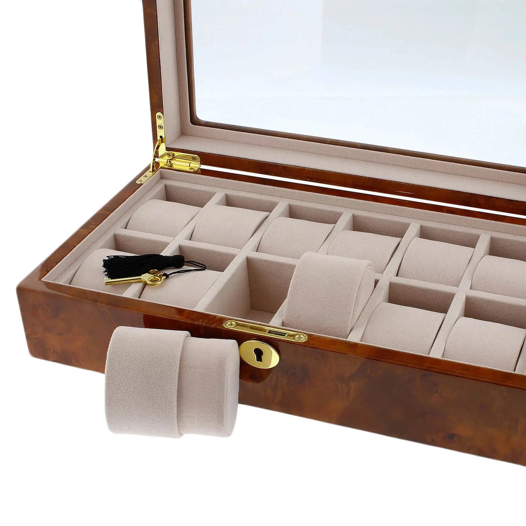 The Aevitas Watch Box for 12 Wrist Watches in Burl Walnut Wood features a glass lid, beige interior, plush holders (one slightly pulled out), and comes with a secure key with black tassel for elegant, organized luxury watch storage.
