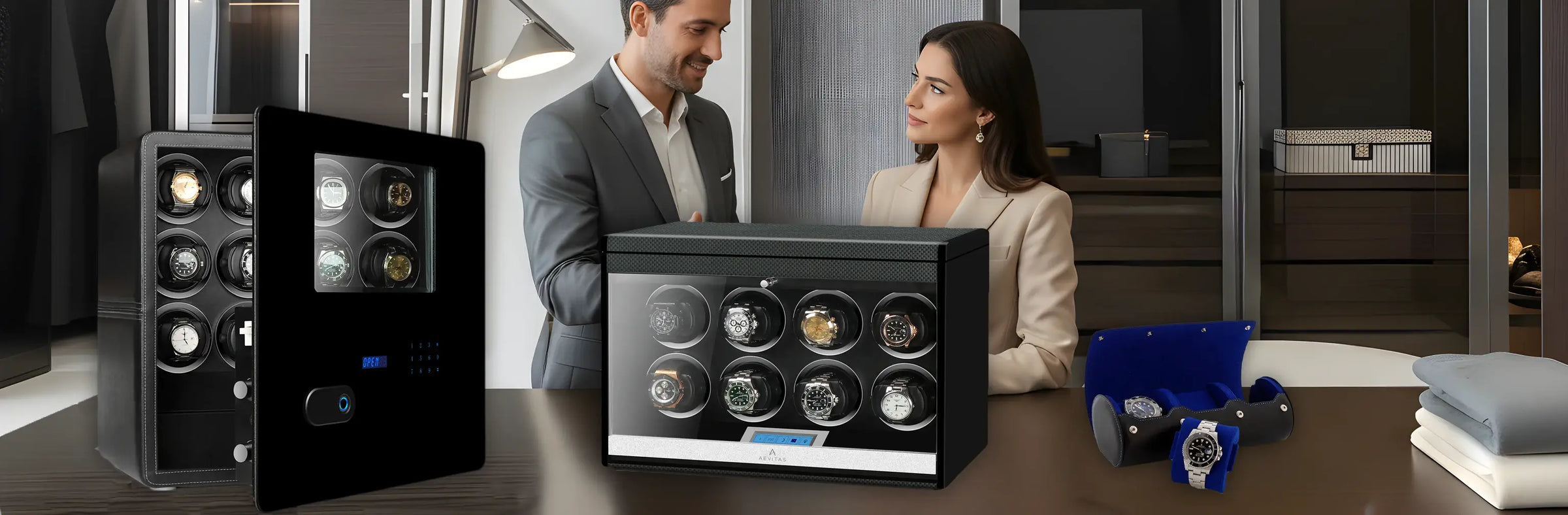 Watches in watch winder box display cases on a table with a man and woman in the background.